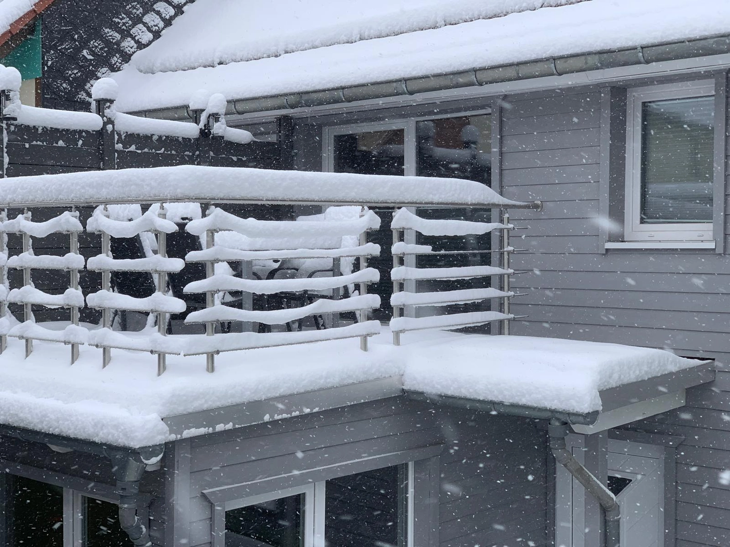 Ecklebe - Ferienwohnung - Eine Nahaufnahme des schneebedeckten Geländers sowie eines Teils des Daches und eines Fensters des Gebäudes.