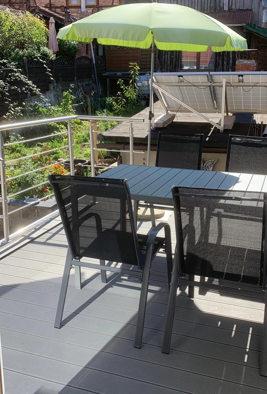 Ecklebe - Ferienwohnung - Ein Balkon oder eine Terrasse mit Esstisch, schwarzen Stühlen, einem Metallgeländer und einem großen Grill im Hintergrund.