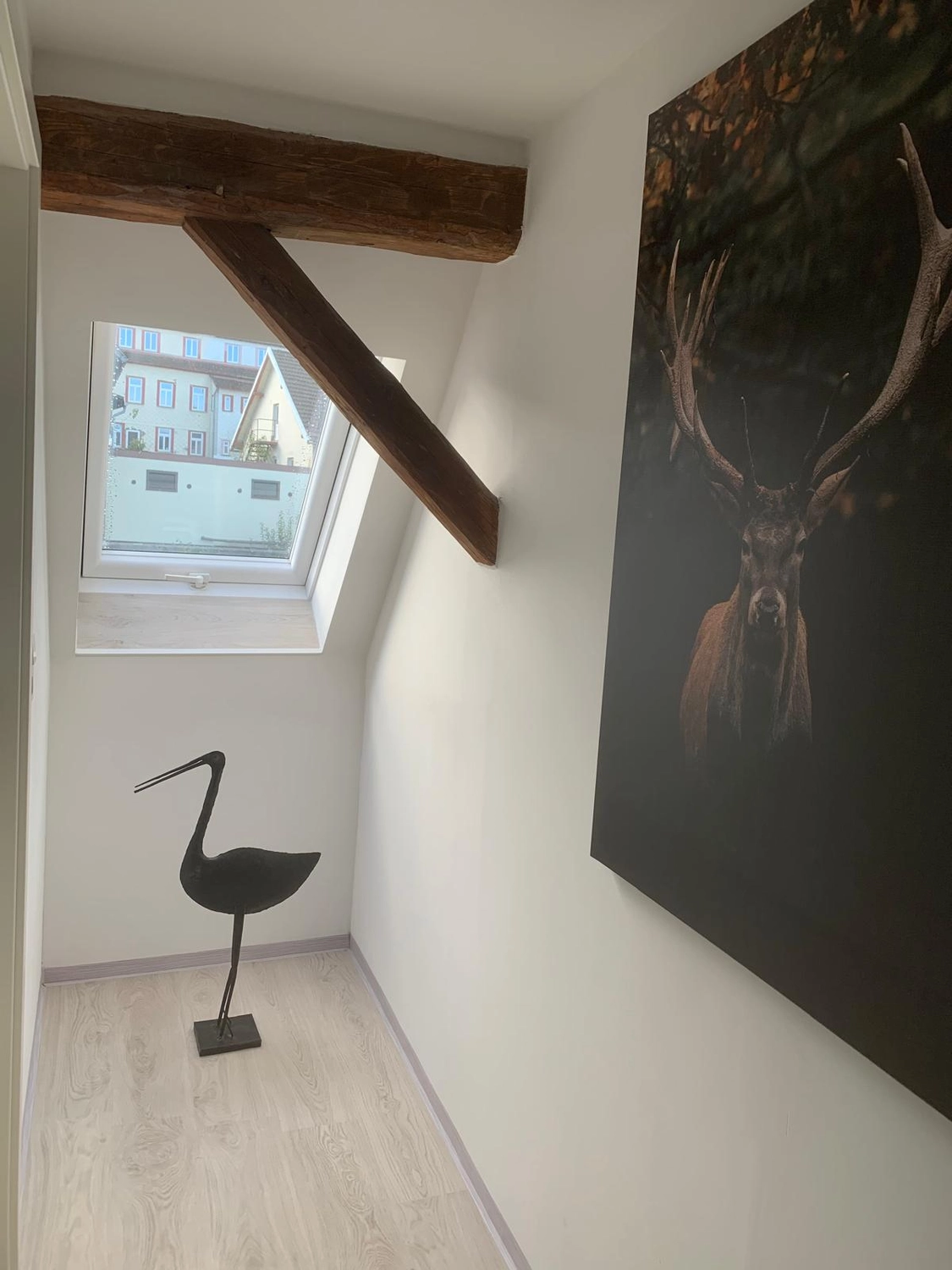 Ecklebe - Ferienwohnung - Ein Flur mit der schwarzen Silhouette einer Vogelstatue und einem dunklen abstrakten Gemälde an der Wand.