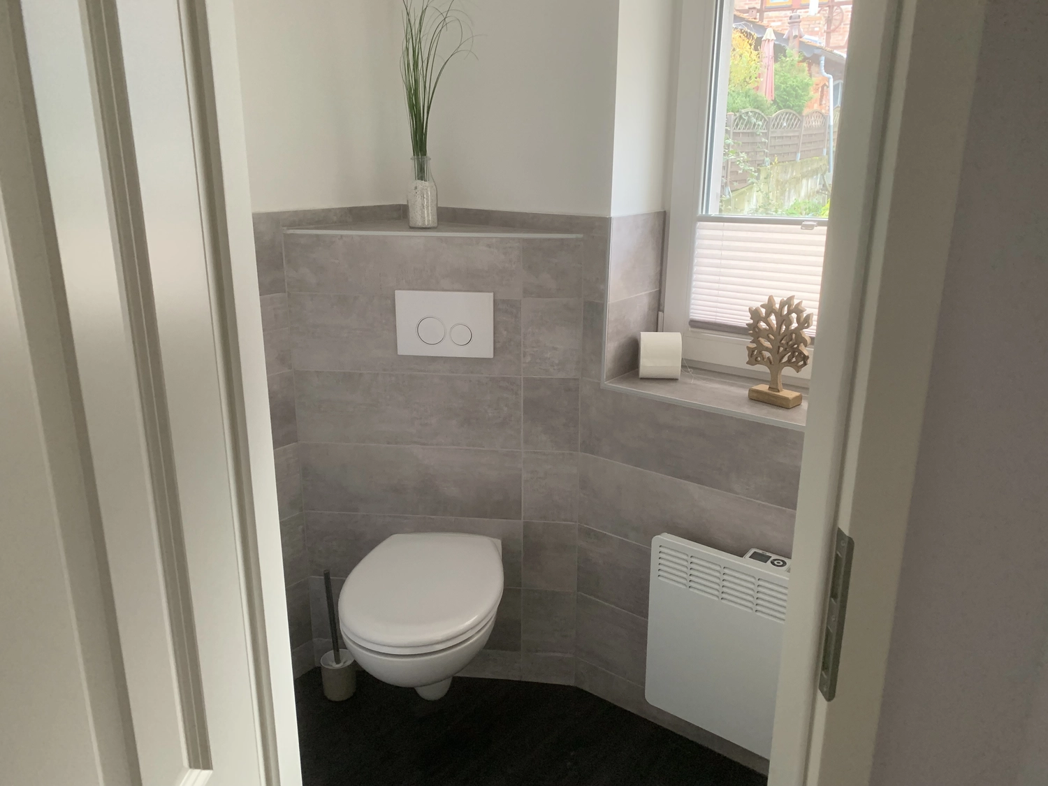 Ecklebe - Ferienwohnung - Eine Badezimmerecke mit Toilette, einer Akzentwand mit Steinmuster und einer Pflanze.