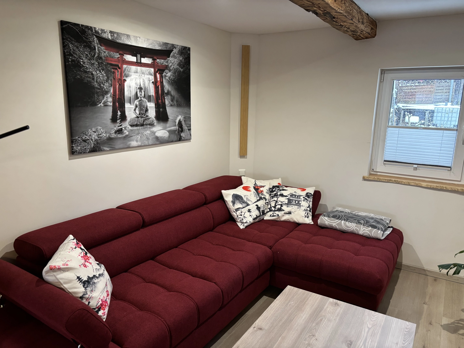Ecklebe - Ferienwohnung - Ein Blick ins Wohnzimmer mit dem roten Sofa und dem Bild des Schrein-Tors.