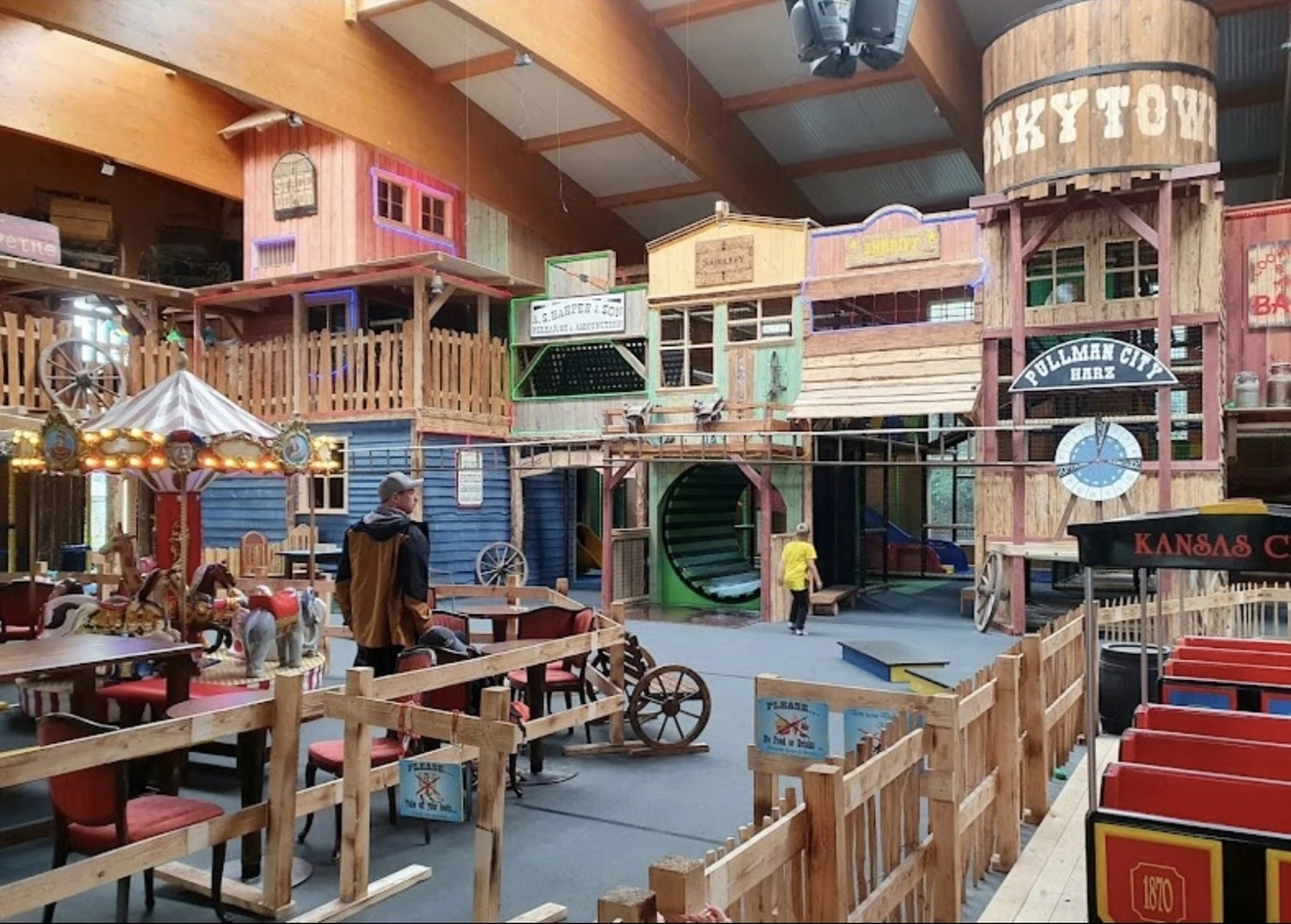 Ecklebe - Ferienwohnung - Außenansicht eines Gebäudes mit einem Schild mit der Aufschrift „KYTOW HOTEL WILD WEST“, im Vordergrund ein hölzerner Steg, eine rote Kanu-Dekoration und Reiter.