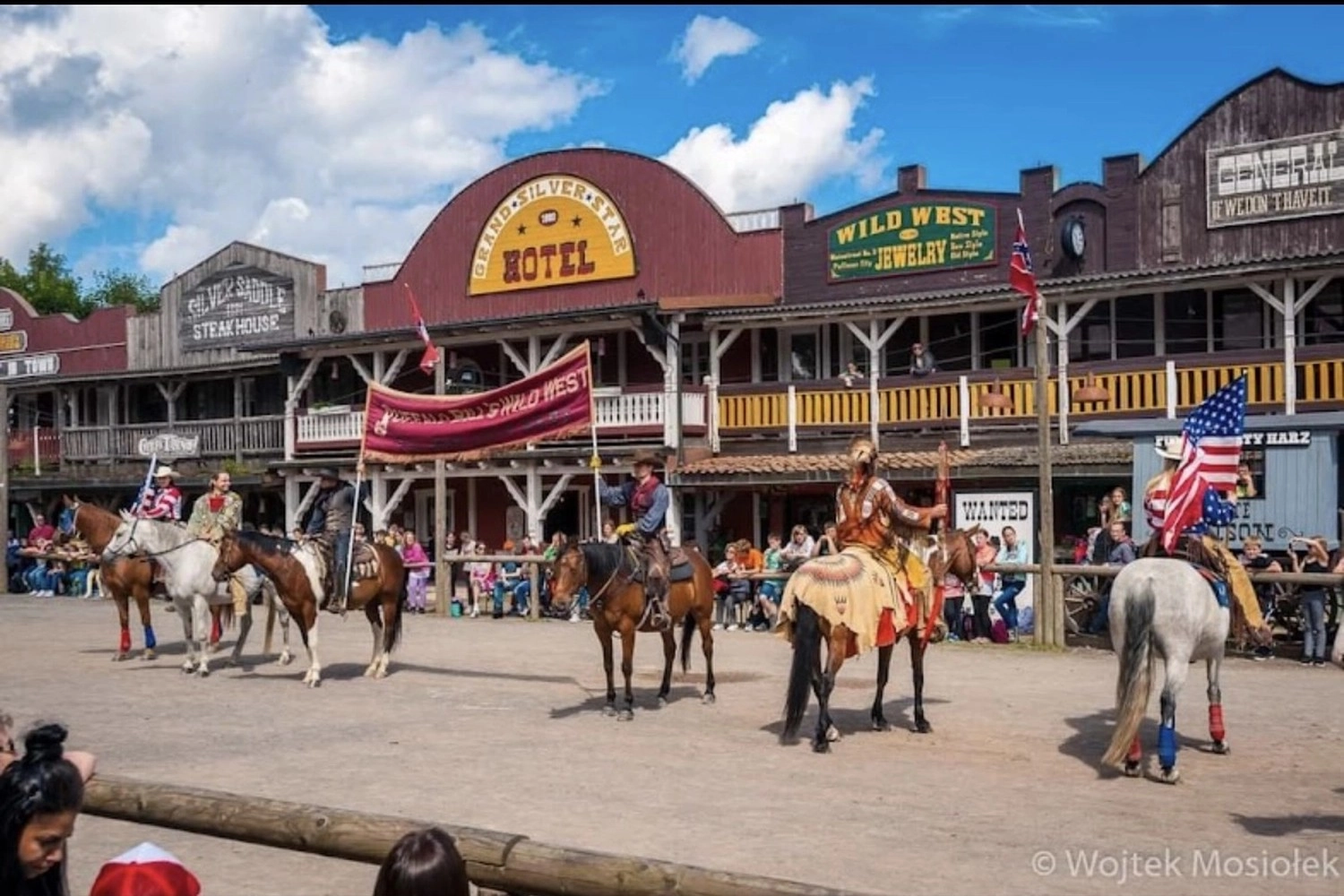 Ecklebe - Ferienwohnung - Ein Indoor-Spielbereich, der wie eine mehrstöckige Westernstadt gestaltet ist und verschiedene Bauwerke, ein kleines Karussell und Holztische umfasst.